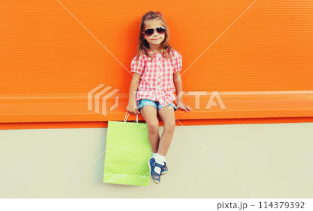 Little girl child with shopping bags posing on city street 114379392