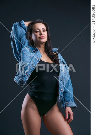 A woman in black tank top and blue denim jacket poses for the camera 114380093