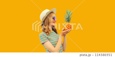 Summer portrait of happy smiling young woman with pineapple fruit on yellow studio background Summer portrait of happy smiling young woman with pineapple fruit on yellow studio background 114380351