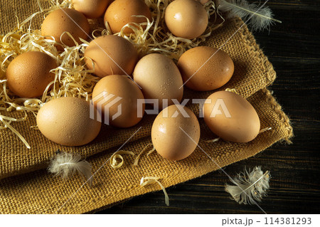 A large pile of eggs with straw and feathers. Chicken eggs are collected to make a healthy breakfast. Harvest concept 114381293