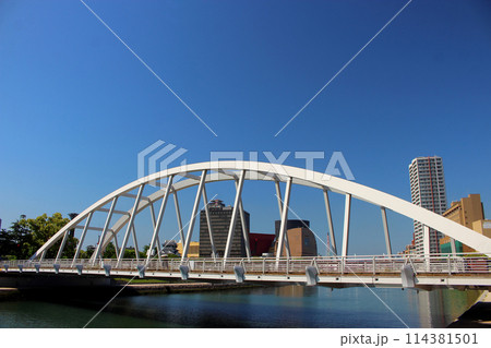 青空下の小倉リバーウォークと紫川に掛かる橋 114381501