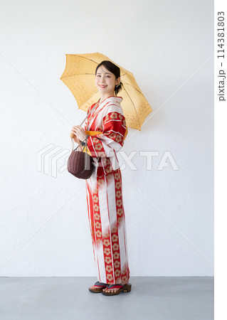 日傘をさす浴衣のかわいい日本人女性　夏の日差しを乗り切る日本の和服　カメラ目線 縦コピースペースあり 114381803