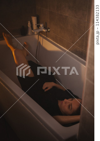 Stressed woman with head bowed in bathtub. Stressed woman with head bowed in bathtub. 114382133