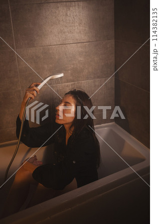 Heartbroken woman sitting in bathtub, water dripping. Heartbroken woman sitting in bathtub, water dripping. 114382135