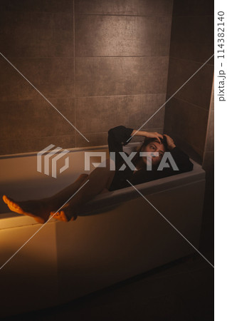 Melancholic woman submerged in bathtub, looking away. 114382140