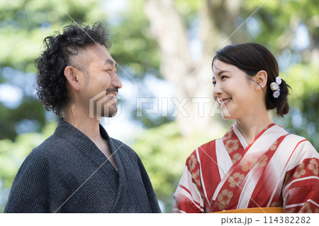夏の緑の屋外で浴衣でデートをする大人の日本人カップル　見つめ合って会話する 114382282