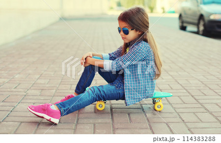 Stylish little girl child posing with skateboard on city street 114383288