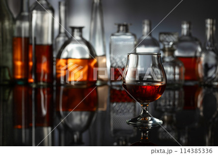 Snifter of brandy on a black reflective background. Snifter of brandy on a black reflective background. 114385336