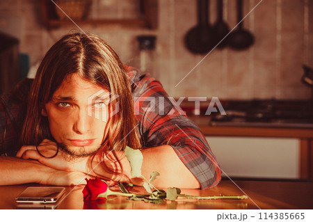 Worried man with rose and mobile phone. 114385665