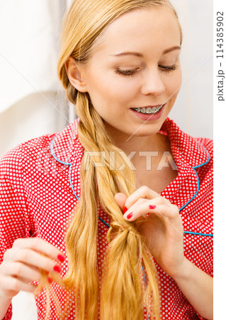Woman doing braid on blonde hair Woman doing braid on blonde hair 114385902