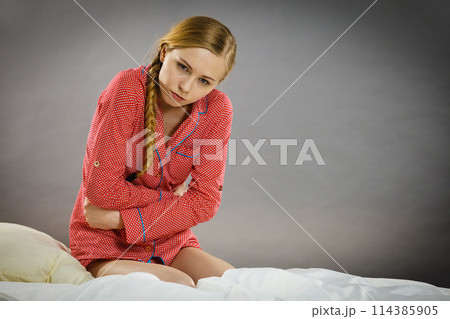 Sad young teenager woman on bed feeling pain Sad young teenager woman on bed feeling pain 114385905