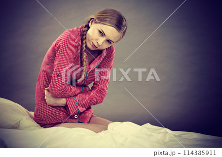 Sad young teenager woman on bed feeling pain Sad young teenager woman on bed feeling pain 114385911