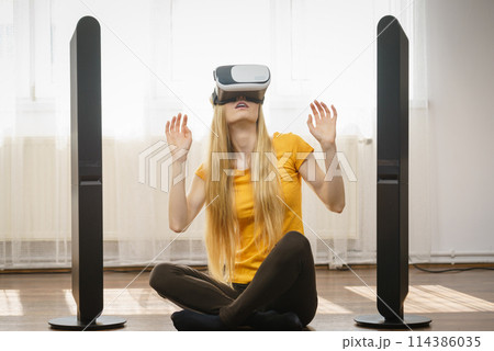 Girl wearing virtual reality goggles at home Girl wearing virtual reality goggles at home 114386035