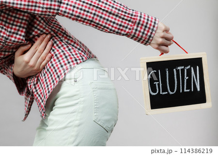 Woman feeling stomach cramps holding gluten board Woman feeling stomach cramps holding gluten board 114386219