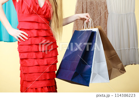 Woman wearing dress holding shopping bags 114386223