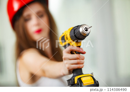 Woman using power driil for work at home Woman using power driil for work at home 114386490
