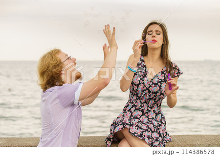 Couple playing with soap bubbles 114386578