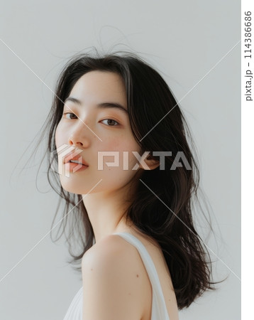Serene young woman with a gentle gaze, embodying calm and simplicity. 114386686