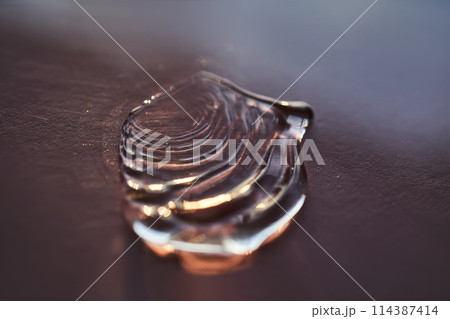 Beautiful volumetric drop of cosmetic product on a dark purple background. 114387414
