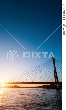 modern cable bridge over Vistula river at sunset, contemporary structures of Warsaw, blue sky on background modern cable bridge over Vistula river at sunset, contemporary structures of Warsaw, blue sky on background 114387823