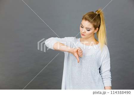 Sad woman showing thumb down gesture Sad woman showing thumb down gesture 114388490