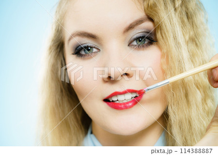 Applying lipstick on fashion model lips Applying lipstick on fashion model lips 114388887