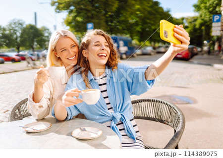 Beautiful woman friends using smartphone selfie together. Fashion, beauty, blogging, tourism. 114389075