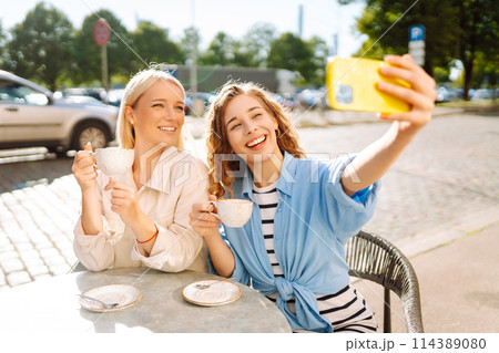 Beautiful woman friends using smartphone selfie together. Fashion, beauty, blogging, tourism. 114389080
