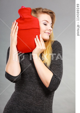 Woman hugs hot water bottle in red fleece cover Woman hugs hot water bottle in red fleece cover 114389149