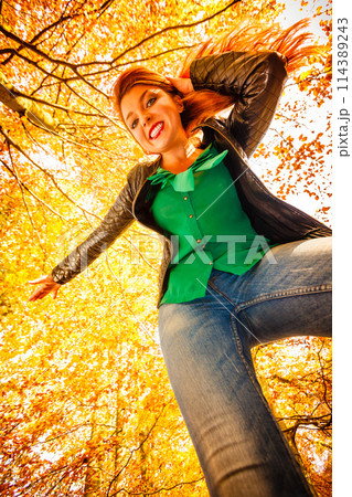Unusual angle of young woman in autumn park 114389243
