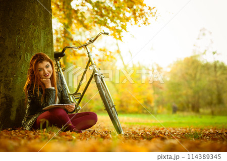 Redhead lady under tree. 114389345