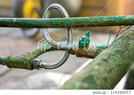 Old garden plumbing with new hose on a cottage garden. 114390457