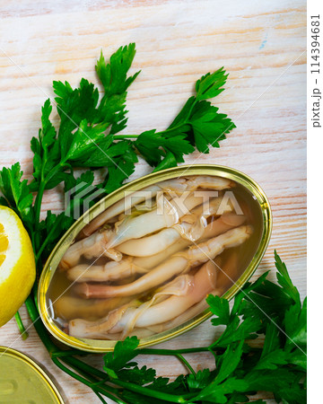 Tasty natural navajas in open tin can served with greens and lemon 114394681