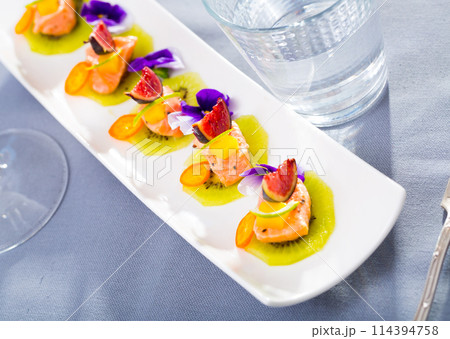 Tasty seafood ceviche from salmon with figs, kiwi and cumquat at plate 114394758
