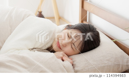 布団の中で痛みを感じる女性 114394983
