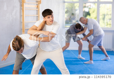 Young guy and man practice wrestling, apply techniques of Aikido and self-defense. 114395170