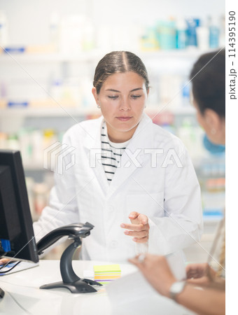 Female pharmacist looking for prescription medicine for woman Female pharmacist looking for prescription medicine for woman 114395190