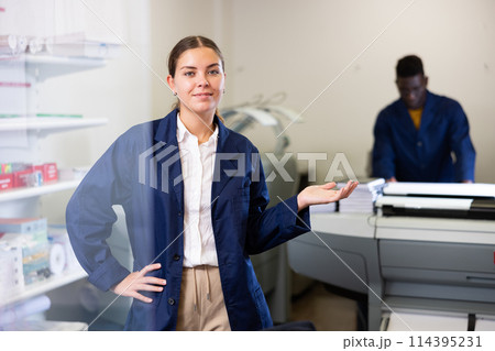 Print shop employee invites a customer to come inside 114395231
