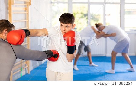 Two men in group boxing classes practicing sparring technique of blowing to body in gym 114395254