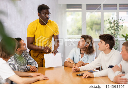 African american showing papers during meeting with male colleagues African american showing papers during meeting with male colleagues 114395305