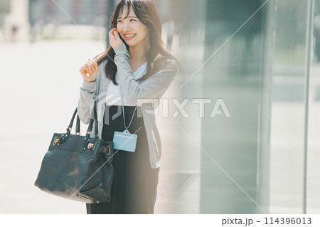 オフィス街を歩くラフな服装の若い働く女性 114396013