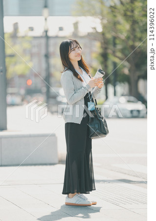 オフィス街を歩くラフな服装の若い働く女性 オフィス街を歩くラフな服装の若い働く女性 114396022