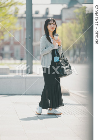 オフィス街を歩くラフな服装の若い働く女性 オフィス街を歩くラフな服装の若い働く女性 114396025