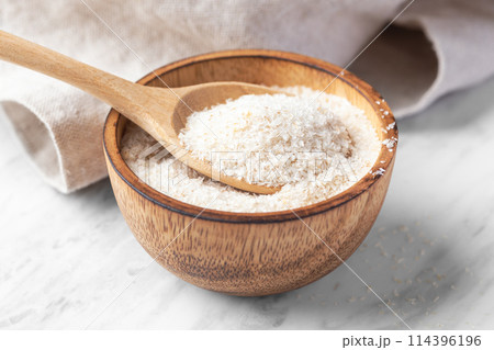 Psyllium husk in spoon and wood bowl, fiber food for diet  on white marble table, closeup 114396196