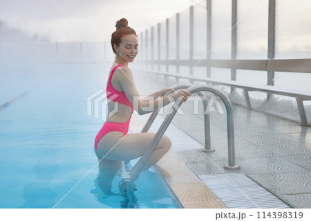 ginger female entering swimming pool and looking down ginger female entering swimming pool and looking down 114398319