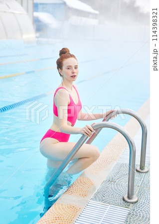 Beautiful gorgeous young woman standing on pool stairs Beautiful gorgeous young woman standing on pool stairs 114398321