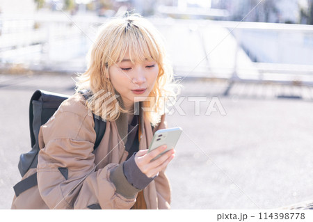 ストリートスナップ　スマホを見ている若い女性　 114398778
