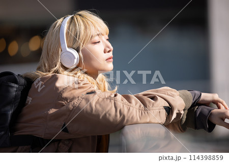ストリートスナップ　音楽を聴いている若い女性 114398859