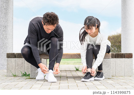 靴紐を結んで運動の準備をするアジア人の男女 114399875