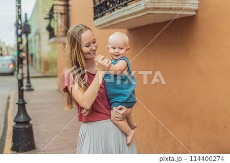 Mother and baby son tourists explore the vibrant streets of Valladolid, Mexico, immersing herself in the rich culture and colorful architecture of this charming colonial town Mother and baby son tourists explore the vibrant streets of Valladolid, Mexico, immersing herself in the rich culture and colorful architecture of this charming colonial town 114400274
